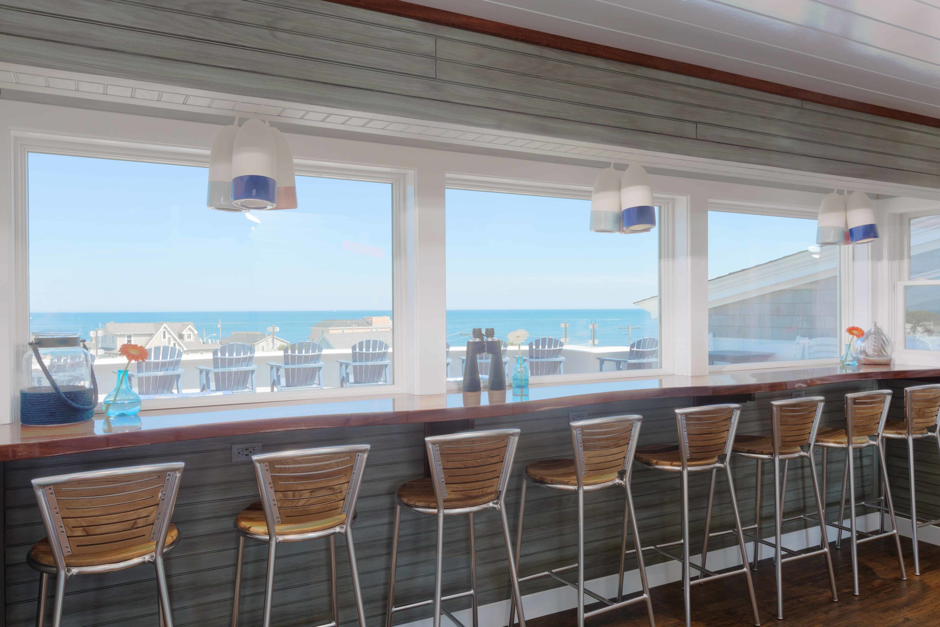 Several wooden chairs look out on an ocean view on the rooftop lounge of one of the most popular Rhode Island hotels. 